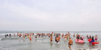 Una folla fa il tifo in spiaggia: oltre cento si tuffano in mare